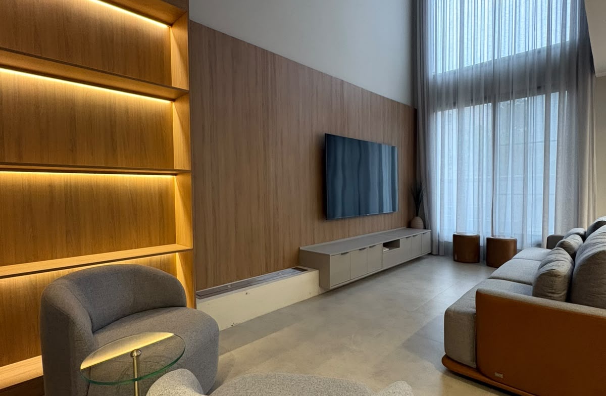 Sala Amaro com estante iluminada, painel de madeira e rack